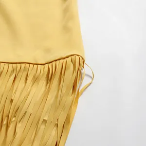 Gedetailleerd overzicht van de delicate gele kwastjesfranjes van een elegante avondjurk met cape