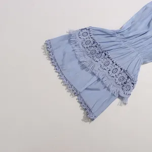 Détail de la broderie anglaise et des franges sur les manches cloches d'une robe bleue
