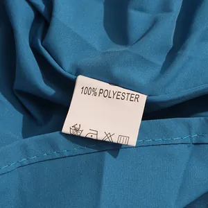 Close-up of a white washing care label on a deep sea blue 100% polyester dress fabric