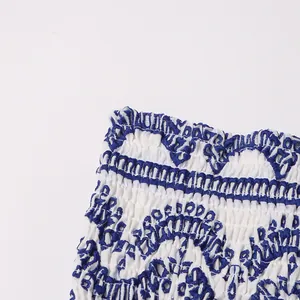 Detail view of smocked fabric with blue bohemian pattern on white summer dress
