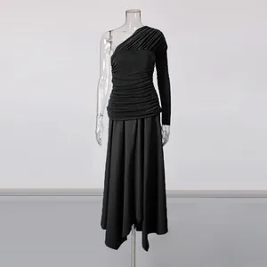 Detail of a black one-shoulder maxi dress with pleated bodice and an irregular hemline