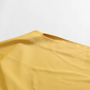 Close-up detail van de uitgesneden halslijn van een elegante gele cape-jurk stof