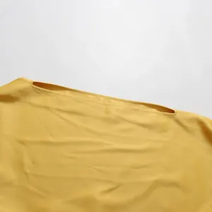 Detailweergave van de elegante asymmetrische halslijn van een gele zomeravondjurk