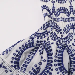 Detailed macro shot of royal blue embroidery and smocked waist on a white cotton Bohemian dress
