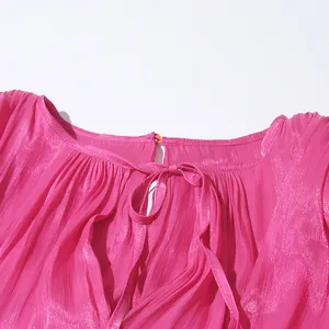 Close-up of fuchsia pleated dress neckline with adjustable tie bow detail