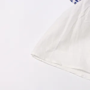 Close-up detail showing the fine texture and blue embroidery of white bohemian dress fabric