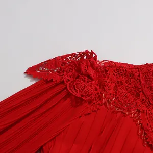Détail macro de la broderie en dentelle rouge fleurie et du tissu plissé sur la robe