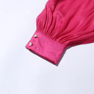 Detail shot of pink pleated dress sleeve cuff featuring two elegant pearl buttons