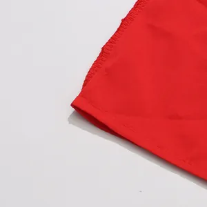 Gros plan détaillé des coutures fines et du tissu rouge vif sur l'ourlet d'une robe d'été.