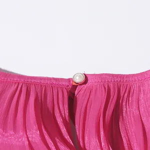 Macro view of a delicate pearl button on fuchsia pleated fabric for a women's summer dress