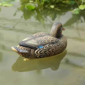 Realistic female mallard duck decoy floating in a natural garden pond with water reflections