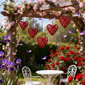 Detail von fünf roten Weidenherzen, die in einem Rosengarten für romantische Deko hängen.