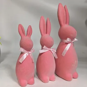 Set of three pink flocked Easter bunny figurines in different sizes with pink silk ribbons