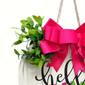 Close-up detail of rustic wooden welcome sign featuring a bright pink bow and green leaves