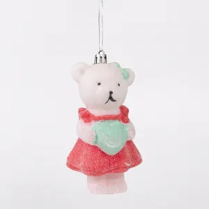 Close-up detail of a white glitter bear Christmas ornament in a red dress