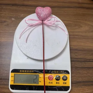Close-up of pink glitter foam heart pick showing a light weight of 2g on a scale
