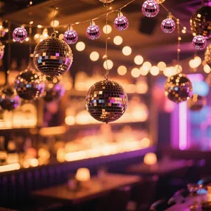 Festive pink and silver mirror disco balls hanging in a warm party atmosphere décor.