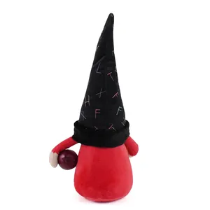 Back view detail of a red plush faceless gnome doll wearing a letter printed black hat