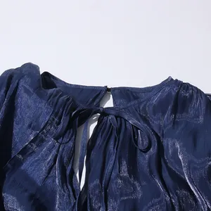 Close-up of a navy blue shimmering fabric dress with a delicate tie-up bow neckline detail