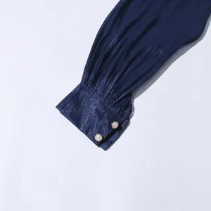 Detail showing pleated sleeve cuff with elegant pearl buttons on dark blue dress