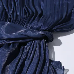 Close-up detail of the elegant pleated texture and waist tie on this navy blue dress.