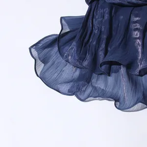 Detail shot of navy blue pleated dress with shimmering metallic threads and ruffled hem