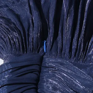 Close-up detail of shimmering blue pleated fabric with a hidden zipper.