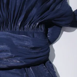 Detailed macro shot of pleated navy blue shimmer fabric on a designer evening dress.