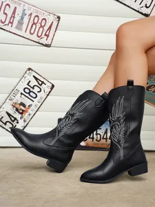 Détail rapproché de bottes de cavalier noires avec broderie de plumes blanches