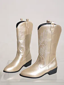 Gros plan sur des bottes de cow-boy dorées avec des broderies blanches raffinées