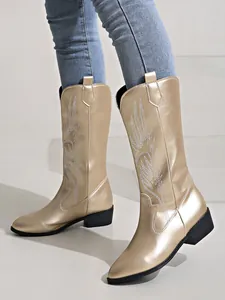 Vue détaillée des bottes de cowboy dorées métallisées avec broderies blanches.