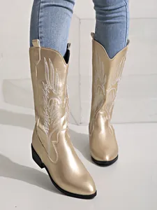 Détail rapproché de bottes de cowboy dorées avec broderie blanche sophistiquée.