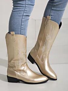 Détail de bottes de cowboy dorées métallisées avec broderie blanche et talon carré