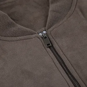 Detailopname van de metalen rits en geribbelde gebreide kraag van het grijze suède jack