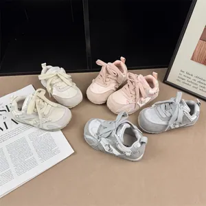 Detailed view of girls' bow-accented sneakers in multiple soft colors with non-slip soles.