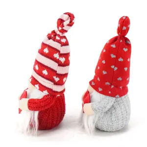 Side view of two Valentine's Day plush gnomes with knitted hats holding red hearts.