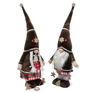 Pair of brown plush gingerbread gnomes with snowflake hats and festive cookie garlands.