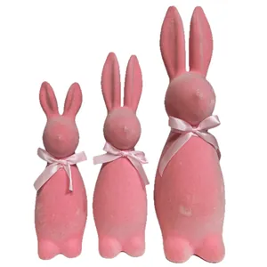 Set of three pink flocked Easter bunny figurines in different sizes on white background.