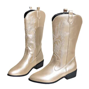 Bottes de cow-boy dorées pour femmes avec broderie florale blanche et bout pointu.