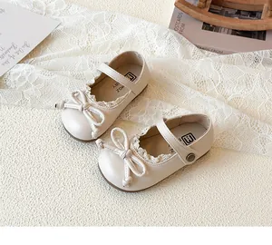 Primo piano di scarpe da principessa per bambina bianco sporco con fiocco e pizzo