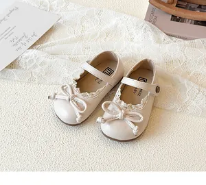 Primo piano di scarpe da principessa avorio per bambine con fiocco e dettagli in pizzo.