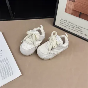 Close-up of girl's white sneakers with delicate bow and pearl details