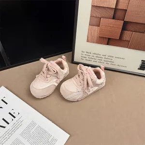 Close-up of stylish pink toddler girl sneakers with delicate bow and pearl accents.