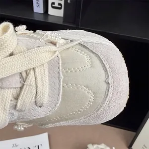 Detail view of girls' beige sneaker featuring elegant pearl flower accents and soft suede texture