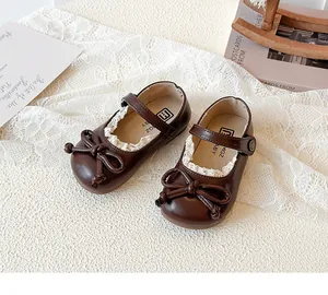 Dettaglio di scarpe Mary Jane marroni per neonata con fiocco e delicato bordo in pizzo