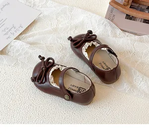 Dettaglio scarpe Mary Jane marroni da neonata con fiocco elegante e pizzo bianco