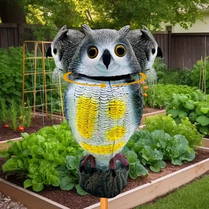 Close-up detail view of rotating head owl decoy in a lush garden for bird control