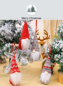 Detailed view of knitted Christmas gnome ornaments hanging on a snowy tree