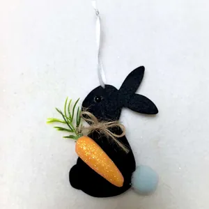 Detailed view of handmade black felt Easter bunny with glitter carrot and pom-pom tail