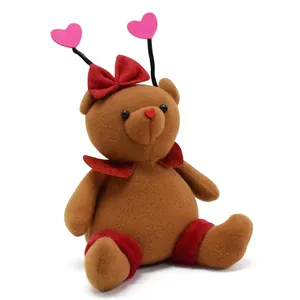 Detailed view of a handmade brown plush bear with heart antennae and red bow tie
